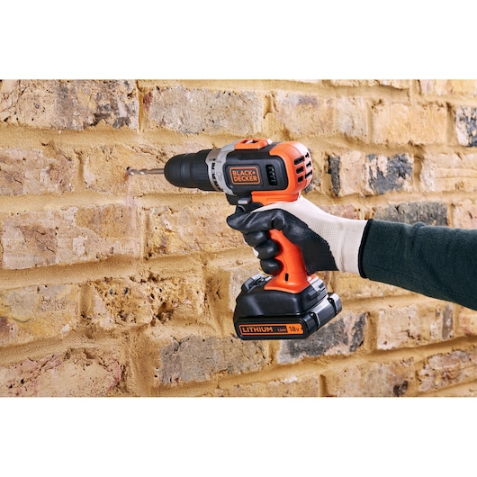 BLACKDECKER BCD003C1 cordless drill in use on a brick wall, orange and black design, photography