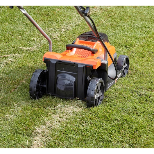 BLACKDECKER lawn mower BCMW33362L1 rear view on grass, orange and black, large wheels, photography