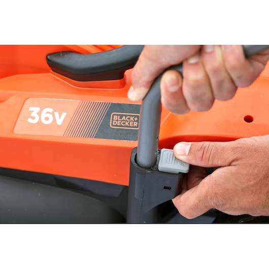 Close-up of BLACK+DECKER BCMW33362L1 lawn mower handle adjustment, orange body with 36v label visible.