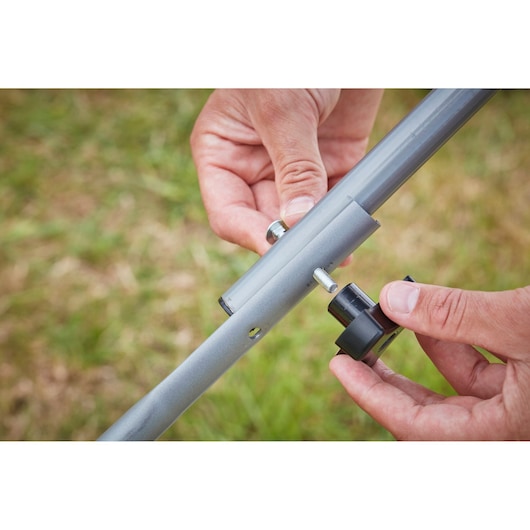 Close up photo of hands assembling BLACKDECKER BCMW33362L1 handlebar with bolt and knob outdoors.