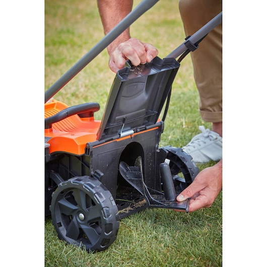 BLACKDECKER BCMW33362L1 lawn mower with rear cover lifted, close-up on grass.