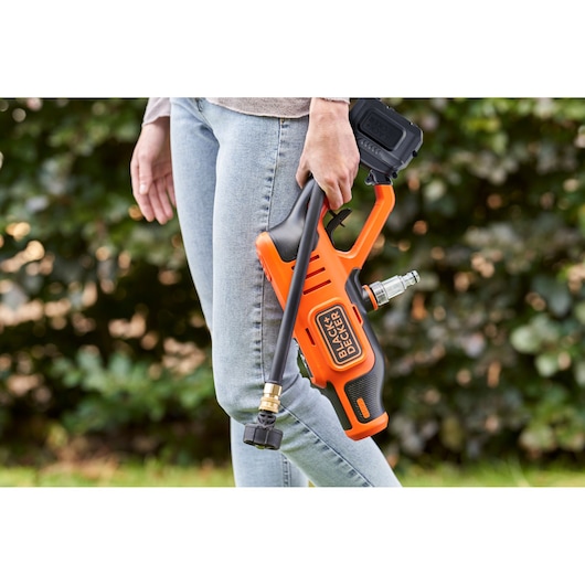 BLACKDECKER BCPC18B cordless pressure washer held by person outdoors.