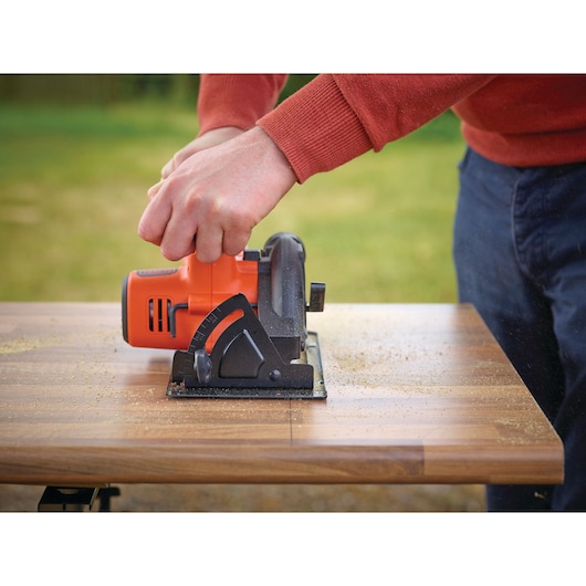 BLACKDECKER BDCCS18C1 cordless circular saw in use cutting wood outdoors, product held by hand.