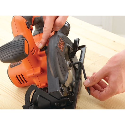 Photo of BLACKDECKER BDCCS18C1 cordless circular saw being adjusted with hex key on wooden surface.