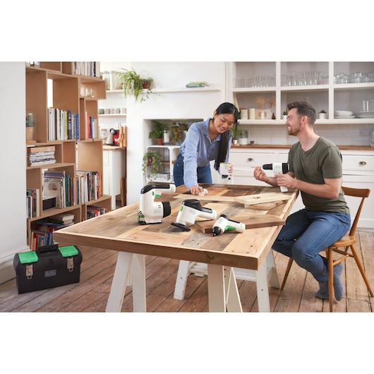 Photo of BLACKDECKER BDST60120 power tools on a wooden table in a home workshop, toolbox visible on floor.