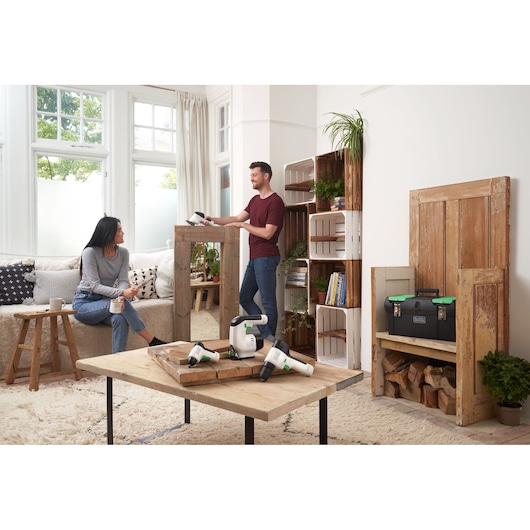BLACKDECKER BDST60120 tool box with green latches on shelf, living room setting with power tools on coffee table.