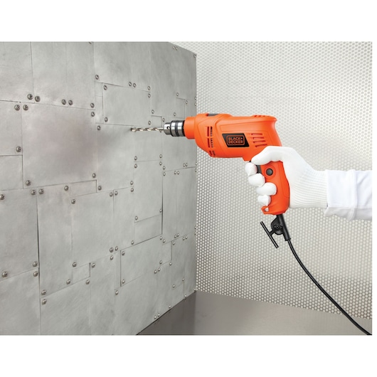 BLACKDECKER BEH201 corded orange drill in use, drilling into a metal panel, close-up side angle.