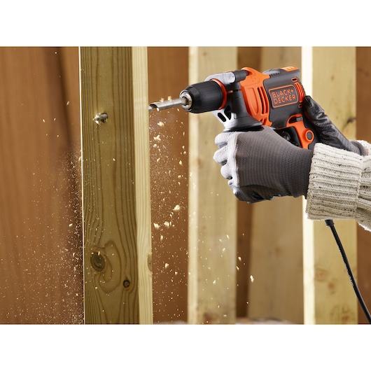 BLACKDECKER BEH550K corded drill used to drill wood, sawdust flying, close-up photography.