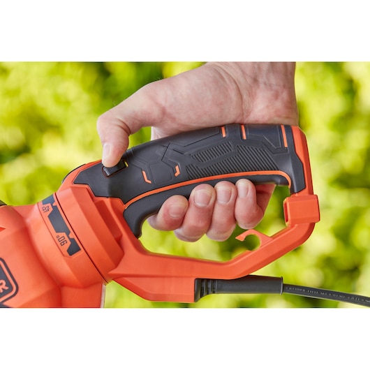 Close-up photo of BLACKDECKER BEHTS551 hedge trimmer handle held by a hand, showing black and orange details.