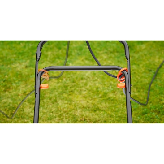 BLACKDECKER BEMW481BH lawn mower handle close-up with orange clips and cord against grass background.