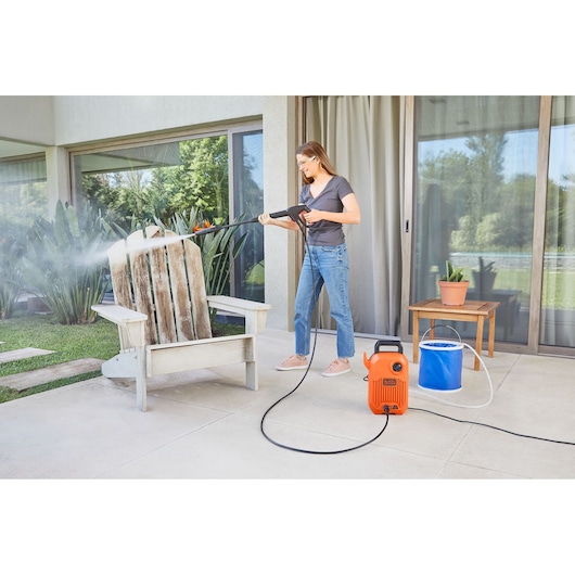 BLACKDECKER BEPW1300 pressure washer used outdoors to clean a wooden chair on patio.