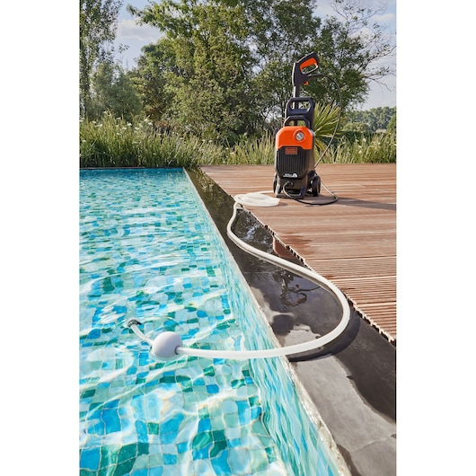 BLACKDECKER BEPW2000 pressure washer with hose in use by a swimming pool on a wooden deck, outdoor angle