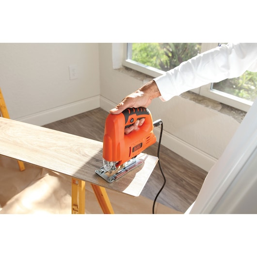 BLACKDECKER BES601 corded jigsaw cutting wood plank indoors, close-up showing tool in use.
