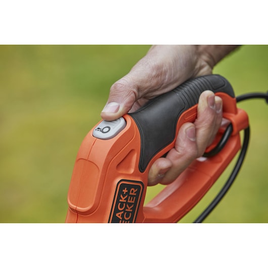 BLACKDECKER BESTE630 photography of orange and black power tool handle with thumb on power button.