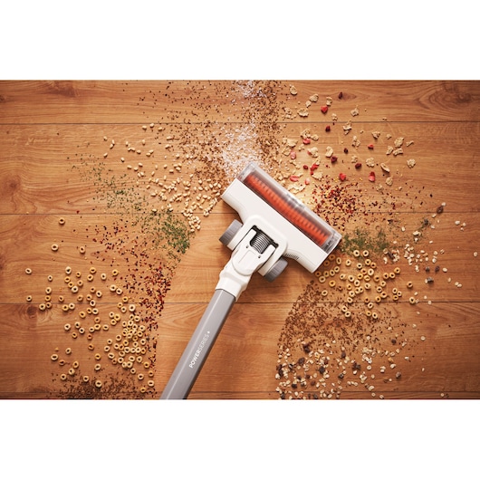 BLACKDECKER BHFEA515J stick vacuum cleaning assorted debris from wooden floor, top view.