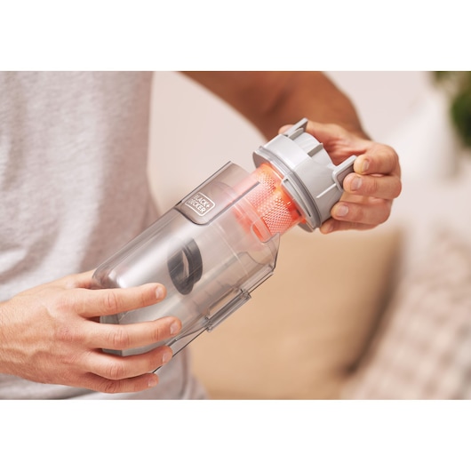 Photo of BLACKDECKER BHFEA520J vacuum dustbin with orange filter being removed, close-up of product detail.
