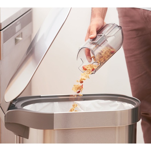 Photo of BLACKDECKER BHFEA520J dustbin being emptied into a stainless steel trash can in a kitchen.