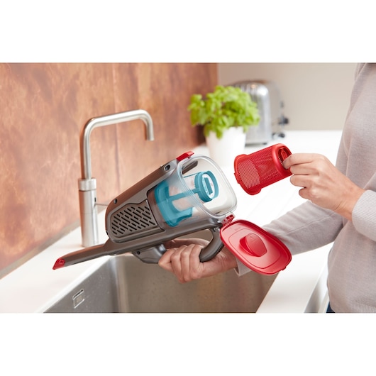 BLACKDECKER BHHV315J handheld vacuum with red filter being cleaned at kitchen sink.