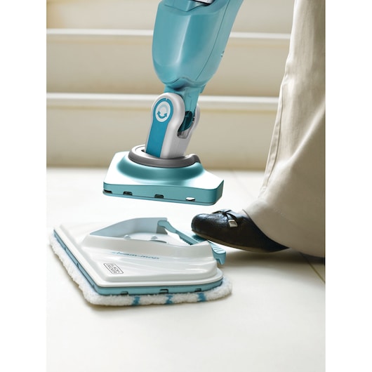 BLACK+DECKER BHSM1610DSM steam mop head being attached with foot, close-up on tiled floor.