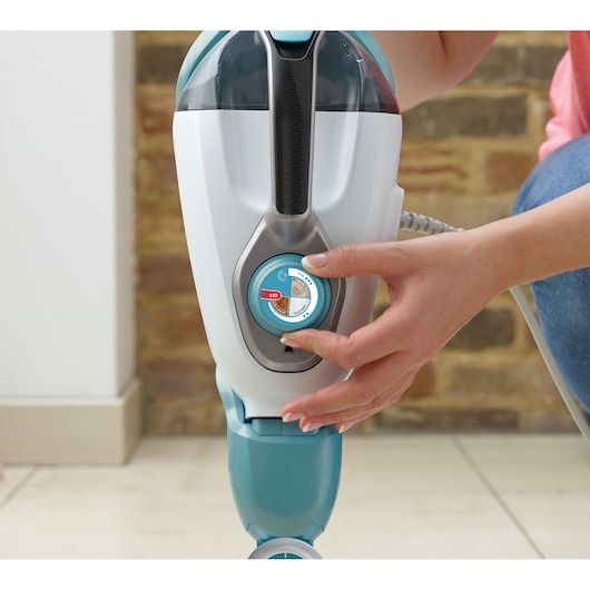 Photo of a BLACKDECKER BHSM1610DSM steam mop with adjustable settings dial being turned by a person’s hand indoors.