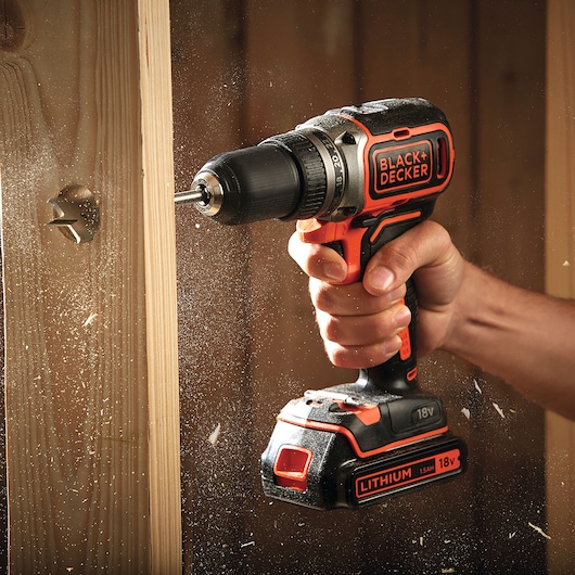 BLACK+DECKER BL186N cordless drill in use, drilling into wood, visible lithium 18V battery.