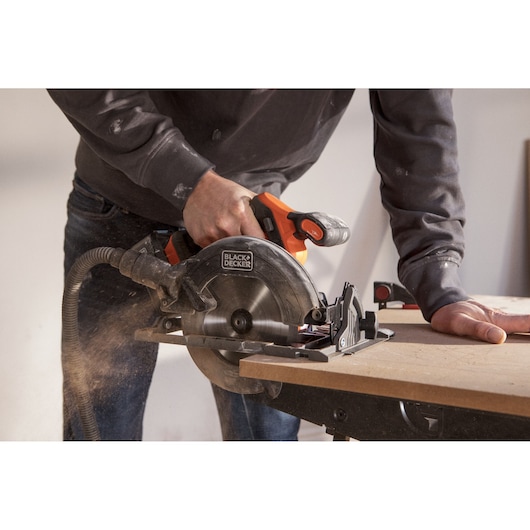 BLACK+DECKER BLCCS78N circular saw used cutting wood, orange and black design, dust extraction hose visible.