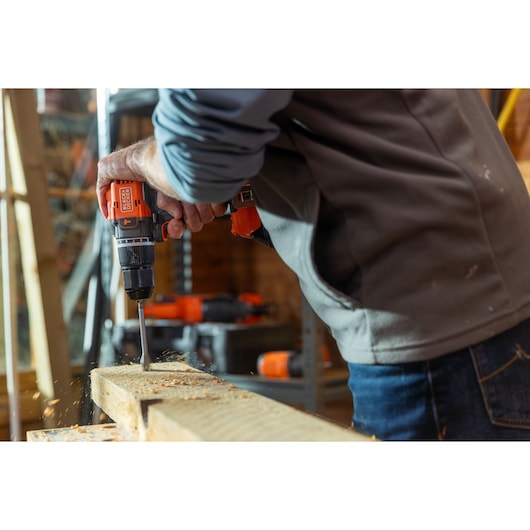 Photo of BLACK+DECKER BLD783E1K cordless drill in use, drilling into a wooden board in a workshop.