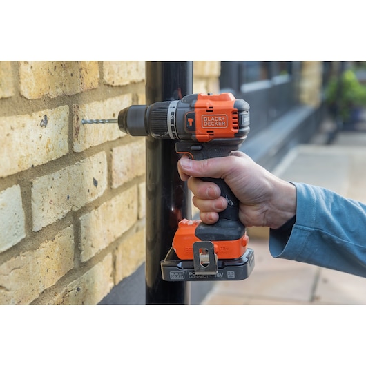 Photo of BLACKDECKER BLD783E1K cordless drill used on a brick wall, orange and black color, product in use.