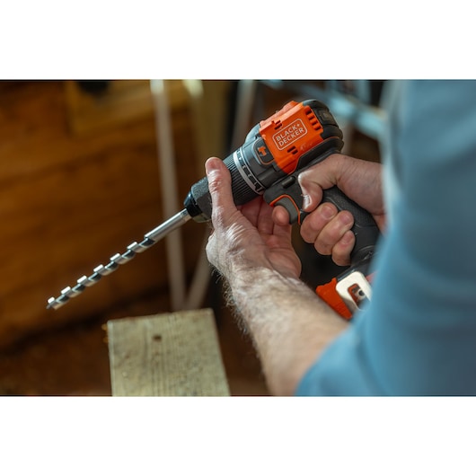 Photo of BLACK+DECKER cordless drill BLD783E1K with auger bit, held by a person while working on wood.