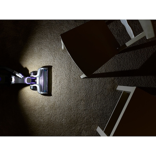 BLACKDECKER CUA525BHP vacuum cleaner head on carpet, overhead angle, cleaning near white chairs