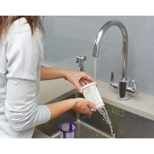 BLACKDECKER CUA525BHP filter being rinsed under faucet at kitchen sink, photography, product cleaning feature.