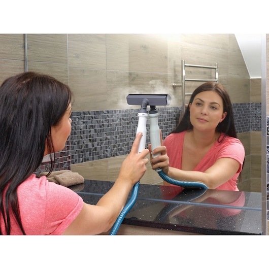 BLACKDECKER FSMH1321 steam cleaner used to clean bathroom mirror, showing handheld device with hose.