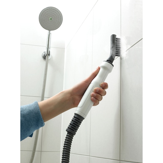 BLACKDECKER FSMHBA steam cleaner accessory cleaning grout in a white tiled shower.