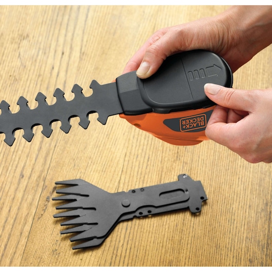 Photo of BLACK+DECKER GSL700 handheld shrub shear with blade attachment, spare blade on wooden surface.