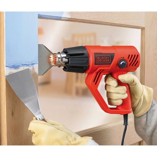 BLACKDECKER KX2001K heat gun in use for paint removal, close-up of tool and gloved hands.