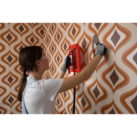 Photo of BLACK+DECKER KX3300 wallpaper steamer in use removing patterned wallpaper.