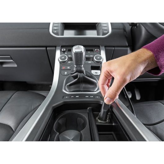 BLACKDECKER NVB12AV handheld vacuum plug inserted in car 12V socket, close-up of center console.