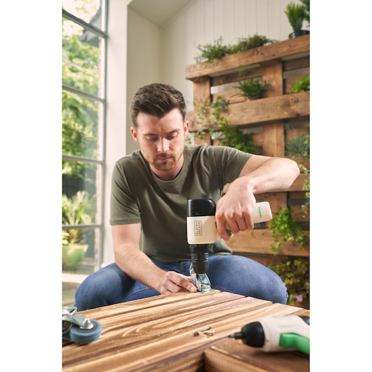 Photo of BLACK+DECKER REVDD12C cordless drill in use assembling wooden furniture indoors.