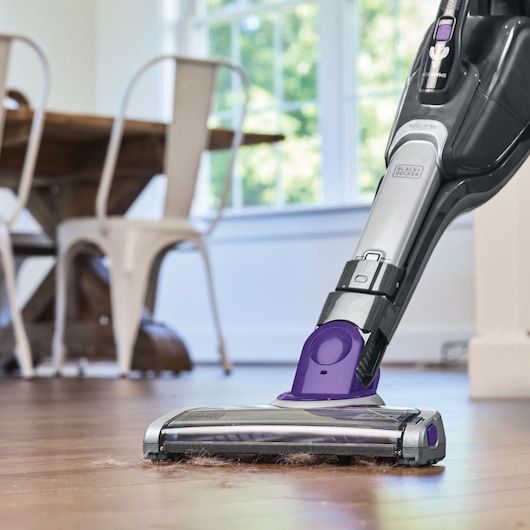 Photo of BLACK+DECKER SVJ520BFSP cordless vacuum cleaning pet hair from hardwood floor in a dining room.