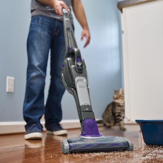 BLACKDECKER SVJ520BFSP stick vacuum cleaning floor near cat and litter box in home setting.