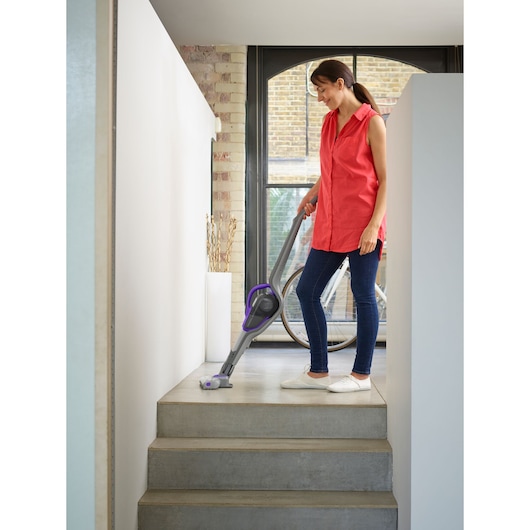 BLACKDECKER SVJ520BFSP cordless stick vacuum with purple accents used on indoor stairs.