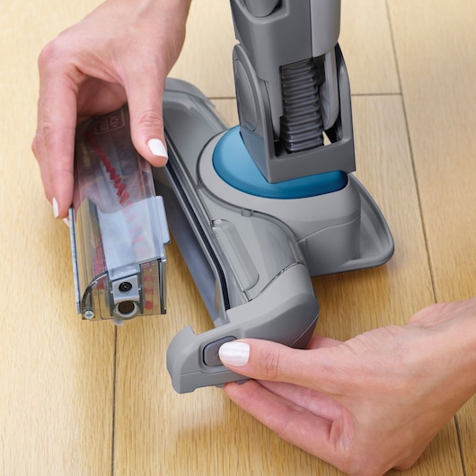 BLACKDECKER SVJ520BFS vacuum cleaner brush removal on a wood floor, close-up.